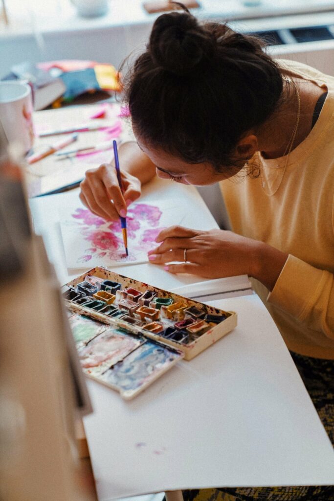 A young woman painting watercolor flowers.