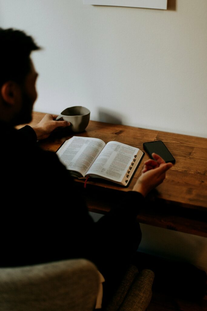 A man sitting at a desk, reading his bible contemplatively.